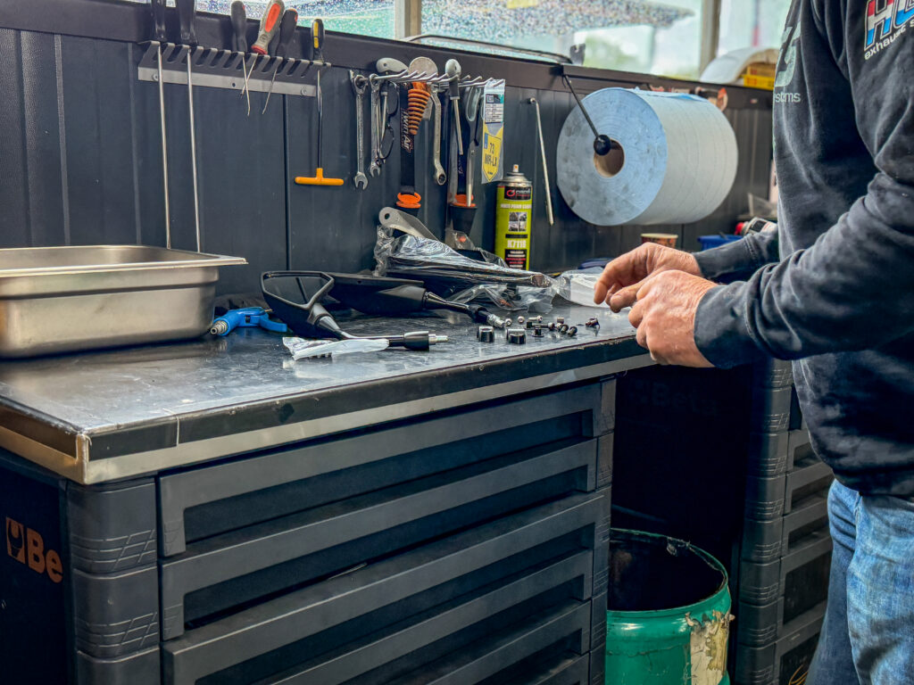 Monteur bezig aan de werkbank in de werkplaats van Vos Oss Motoren